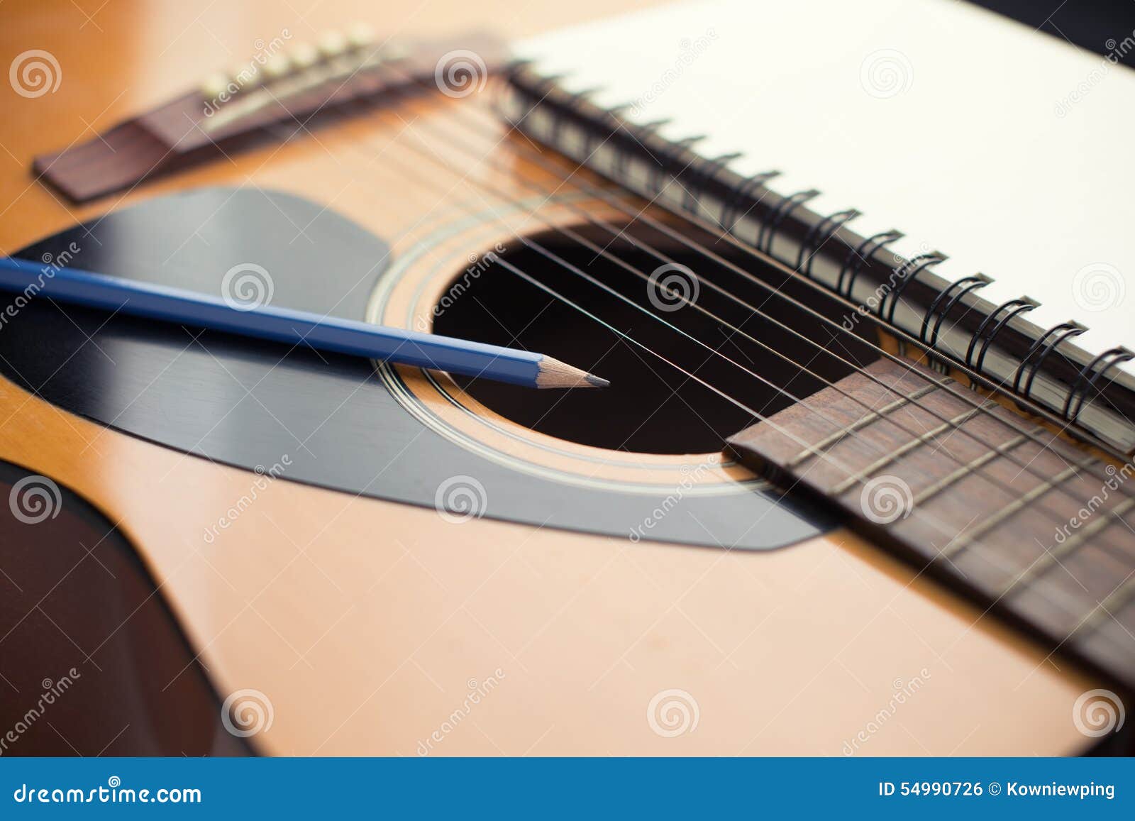 Acústico, cuaderno y lápiz en la guitarra, escribiendo música