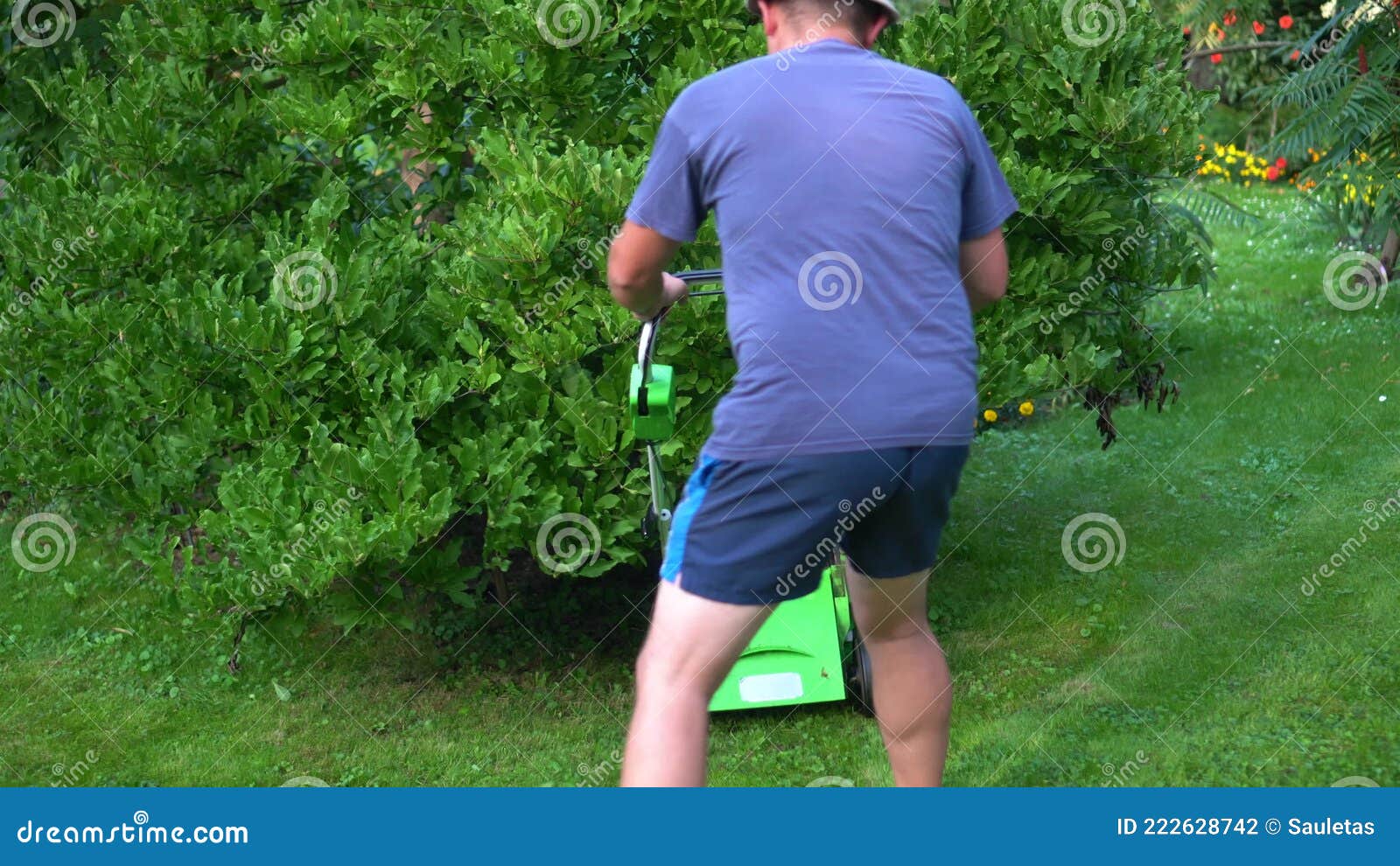 Cuidadoso Tipo En Pantalones Cortos Cortando Césped Alrededor Del Monte En El Jardín Metrajes imagen