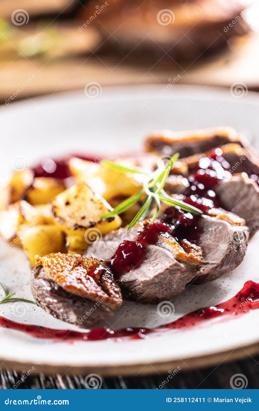 culinarily prepared duck breast with baked potatoes and cranberry cauce