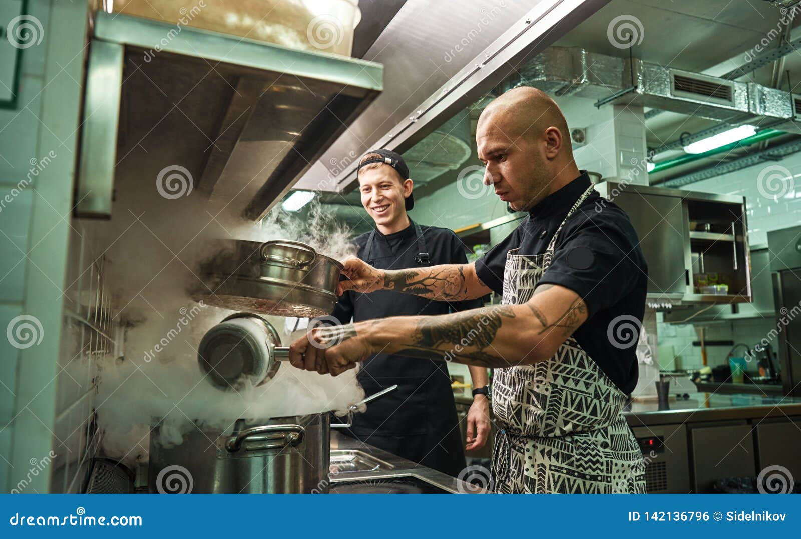 culinary school. handsome and confident chef teaching how to cook his two assistants in a restaurant kitchen