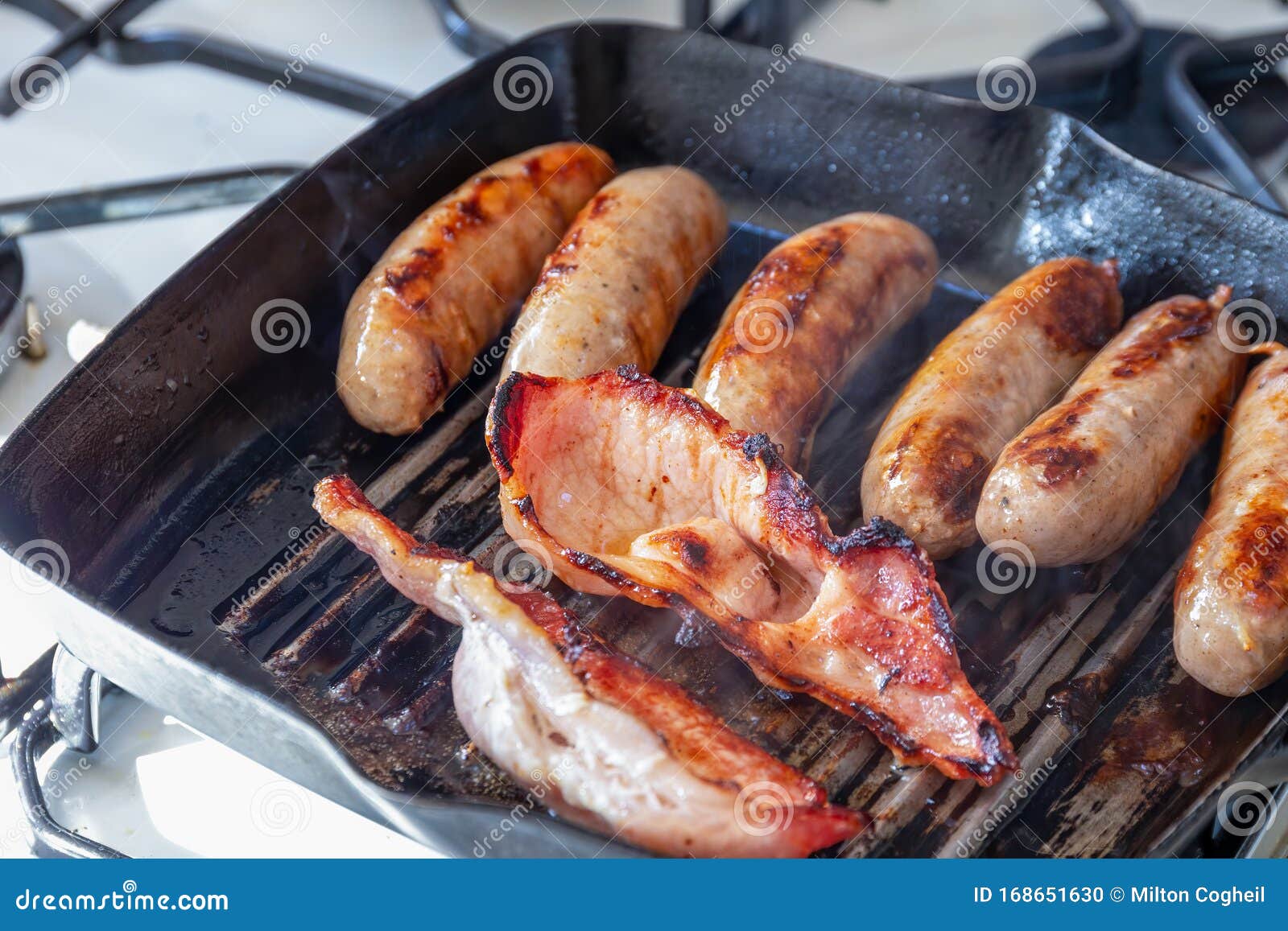 Cumberland Sausages and Bacon Cooking in a Griddle Pan Stock Photo