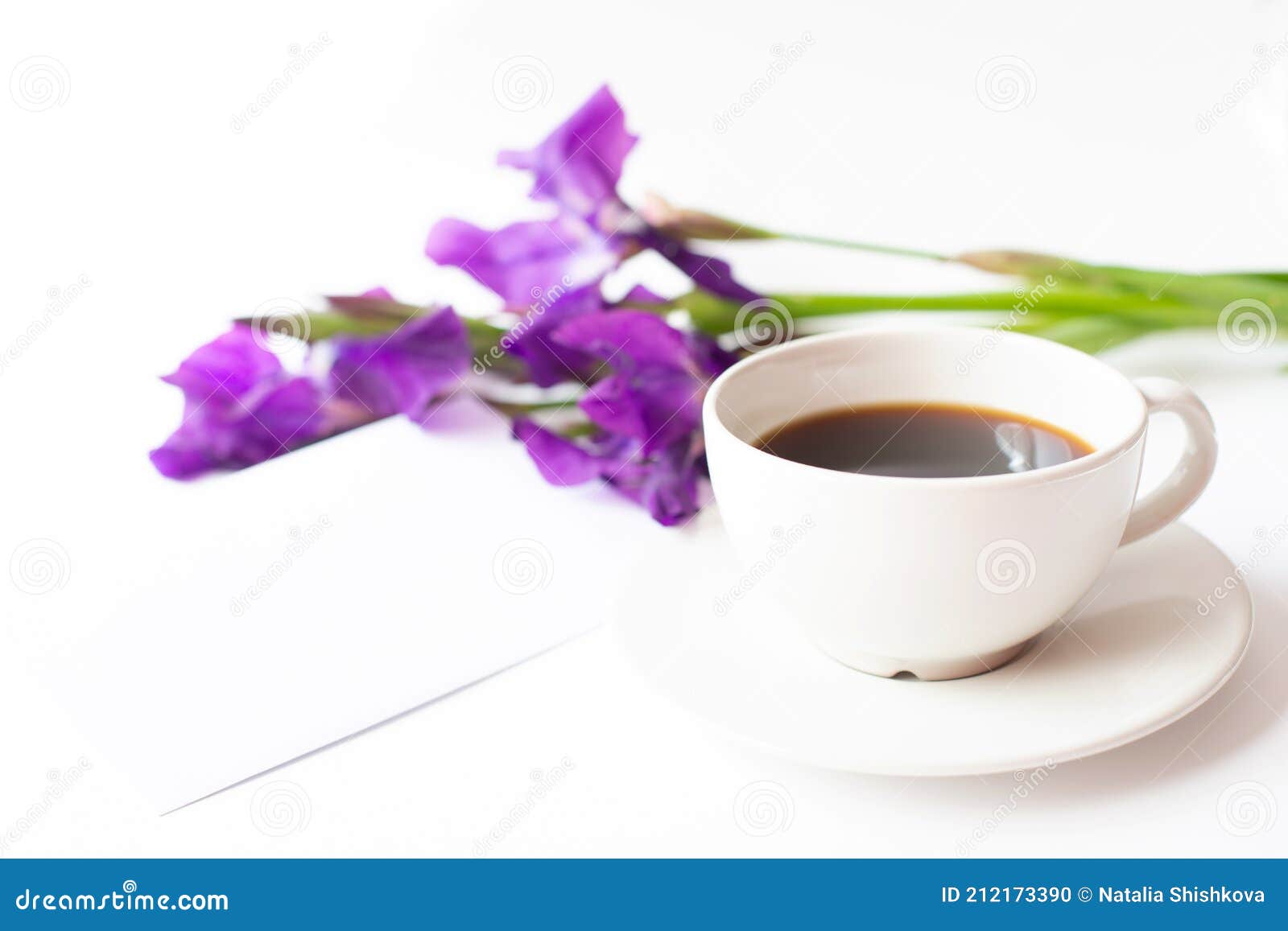 a cup with black coffee and a bouquet of iris flowers are on a light background.