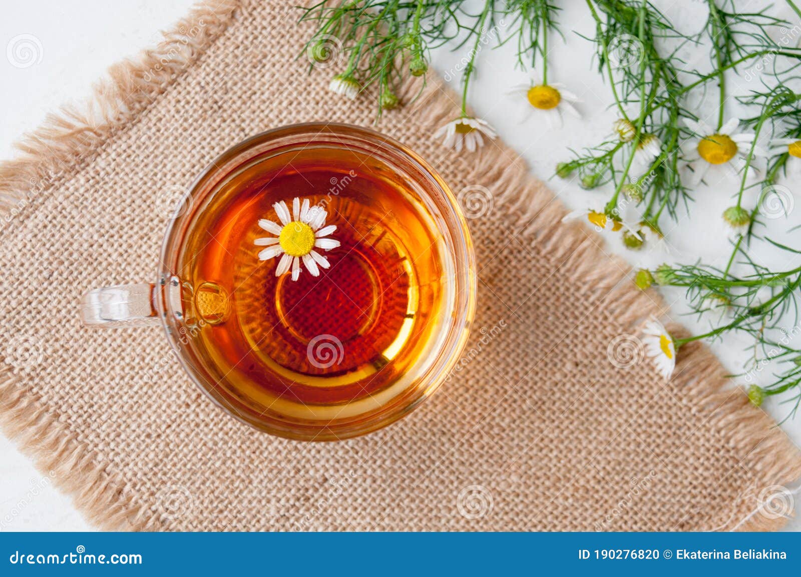 A Cup of Chamomile Tea and Chamomile Flowers on the Table, Top View
