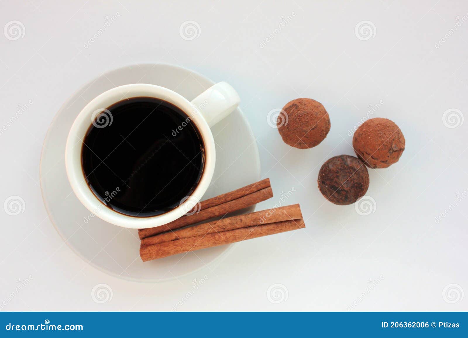 cup of coffee with chocolate truffels and cinnamon sticks on white background.