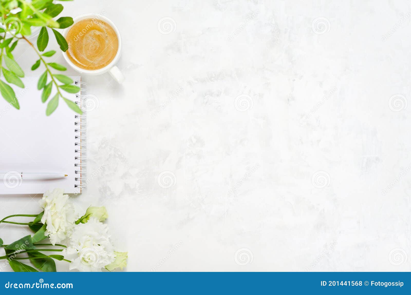 cup of coffee, eustoma, pistachio greenery, notepad and pen on concrete background
