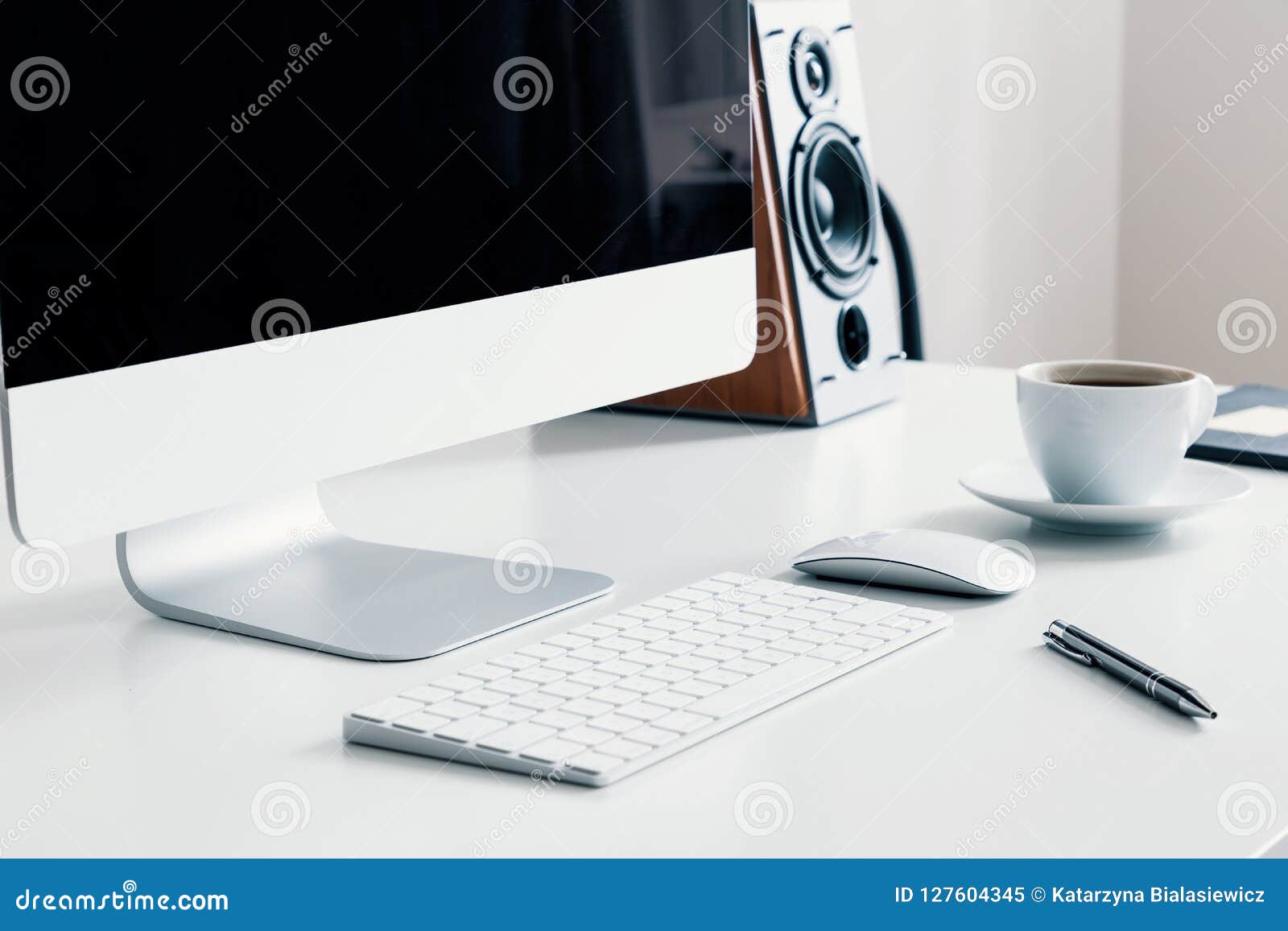 cup of coffee, keyboard and desktop computer on desk in white home office interior. real photo