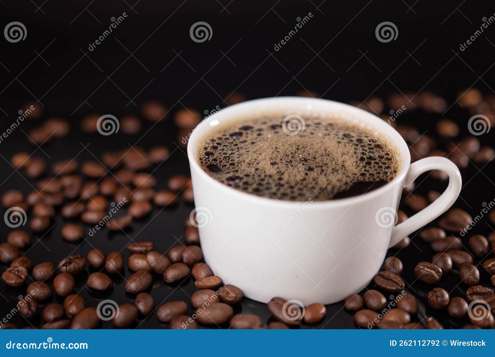 Cup of Foamy Coffee among a Heap of Roasted Beans Stock Photo Image