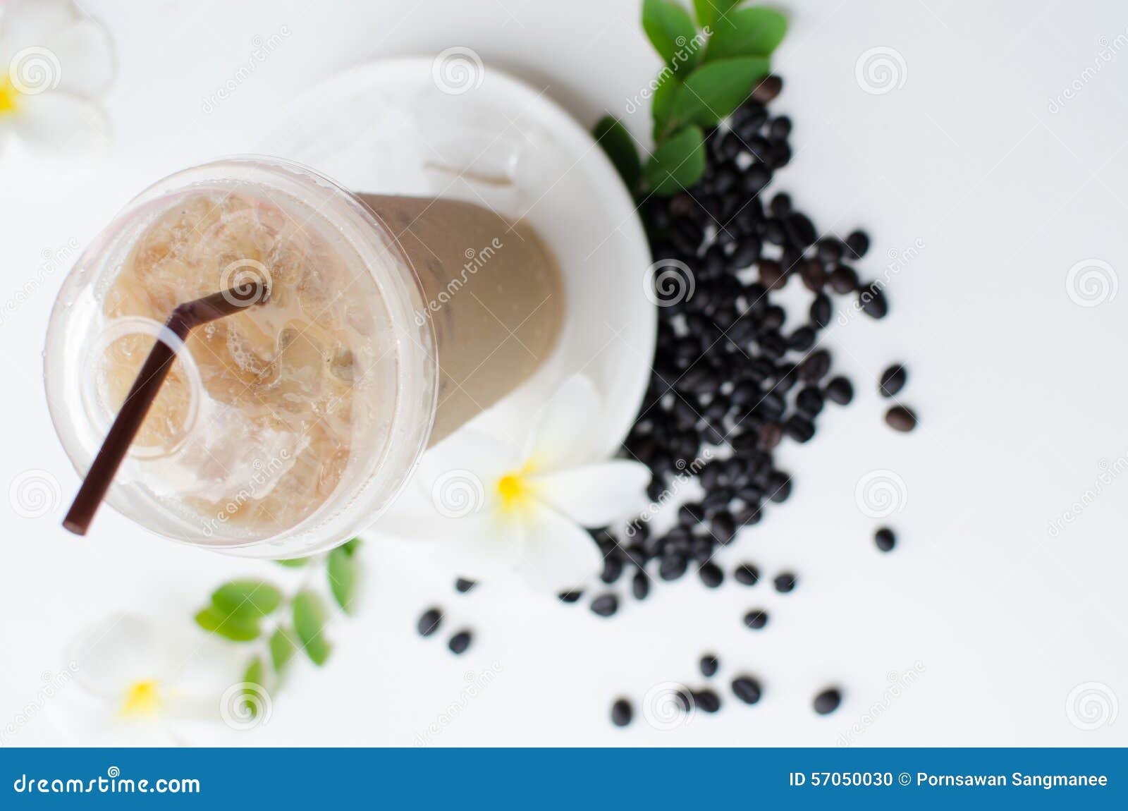 Cup ice coffee and white and yellow Plumeria flower on wood table