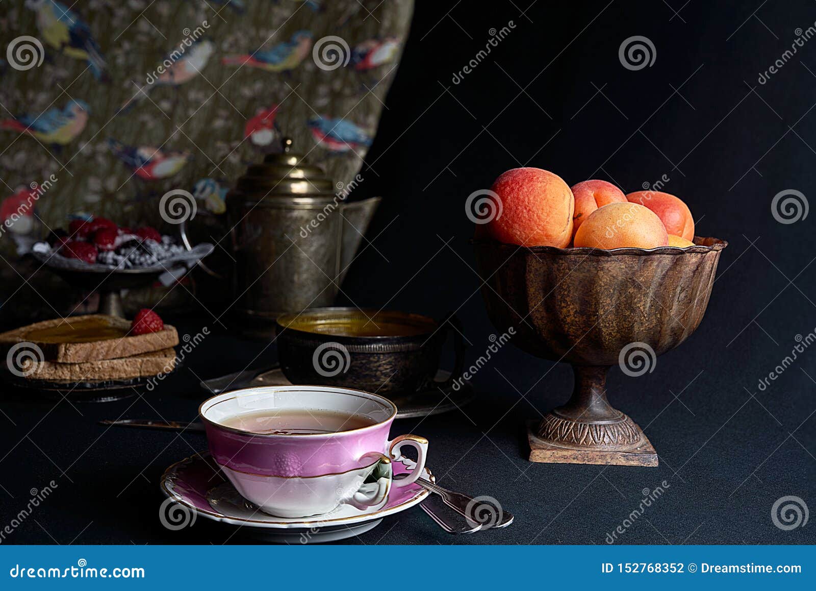 a cup of tea accompanied by fresh apricots, apricot jam and a tray of berries