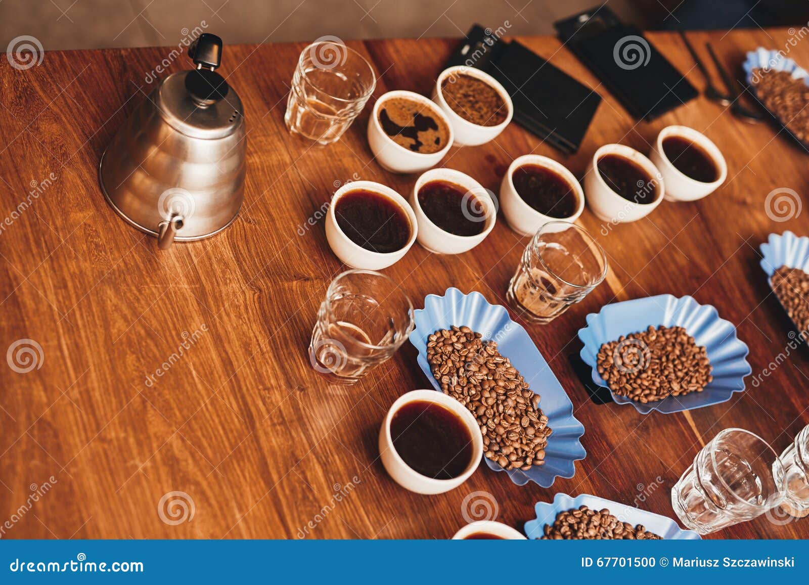 cups of coffee, beans, and kettle on table for tasting