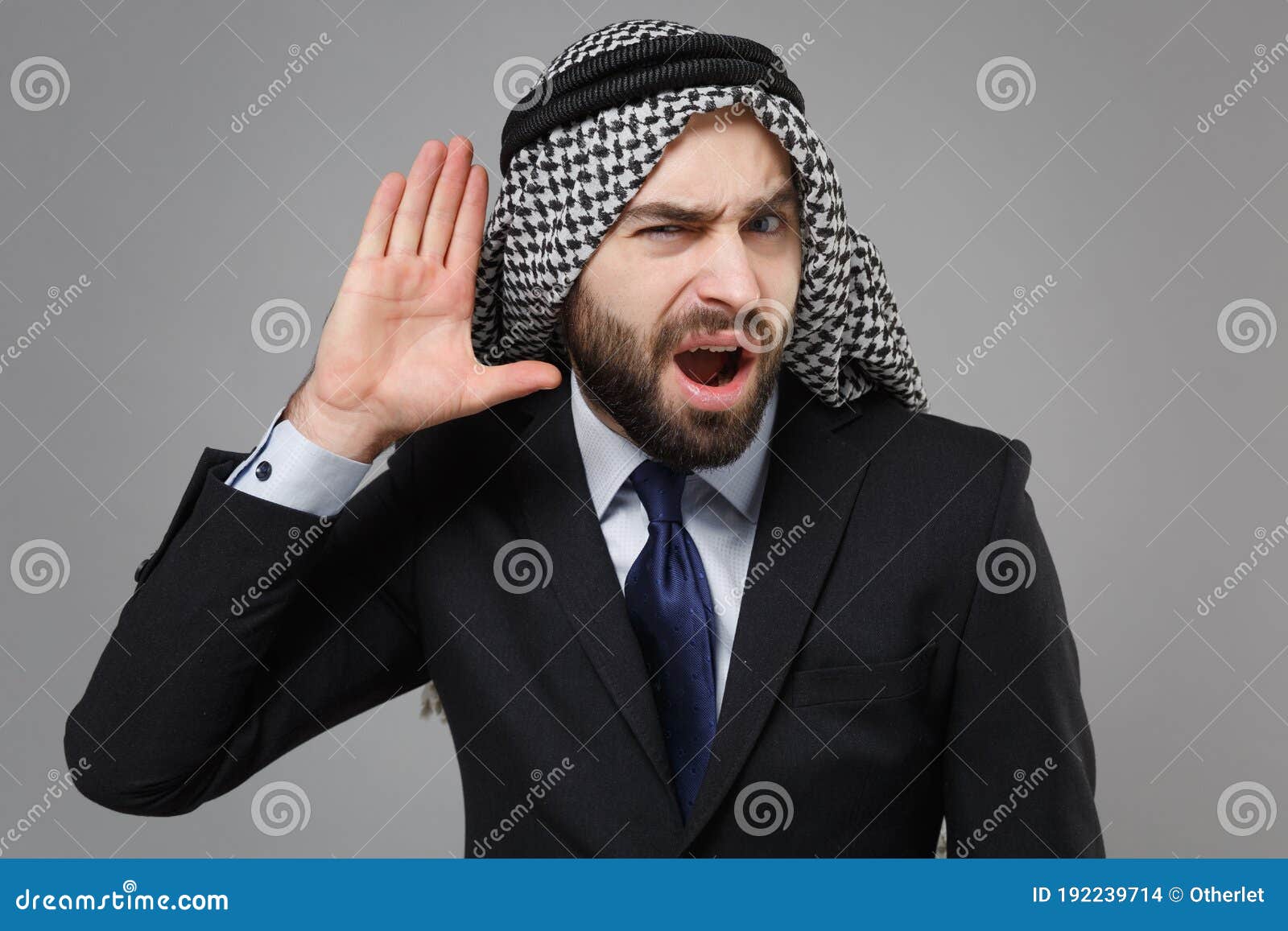 curious arabian muslim businessman in keffiyeh kafiya ring igal agal classic black suit  on gray background