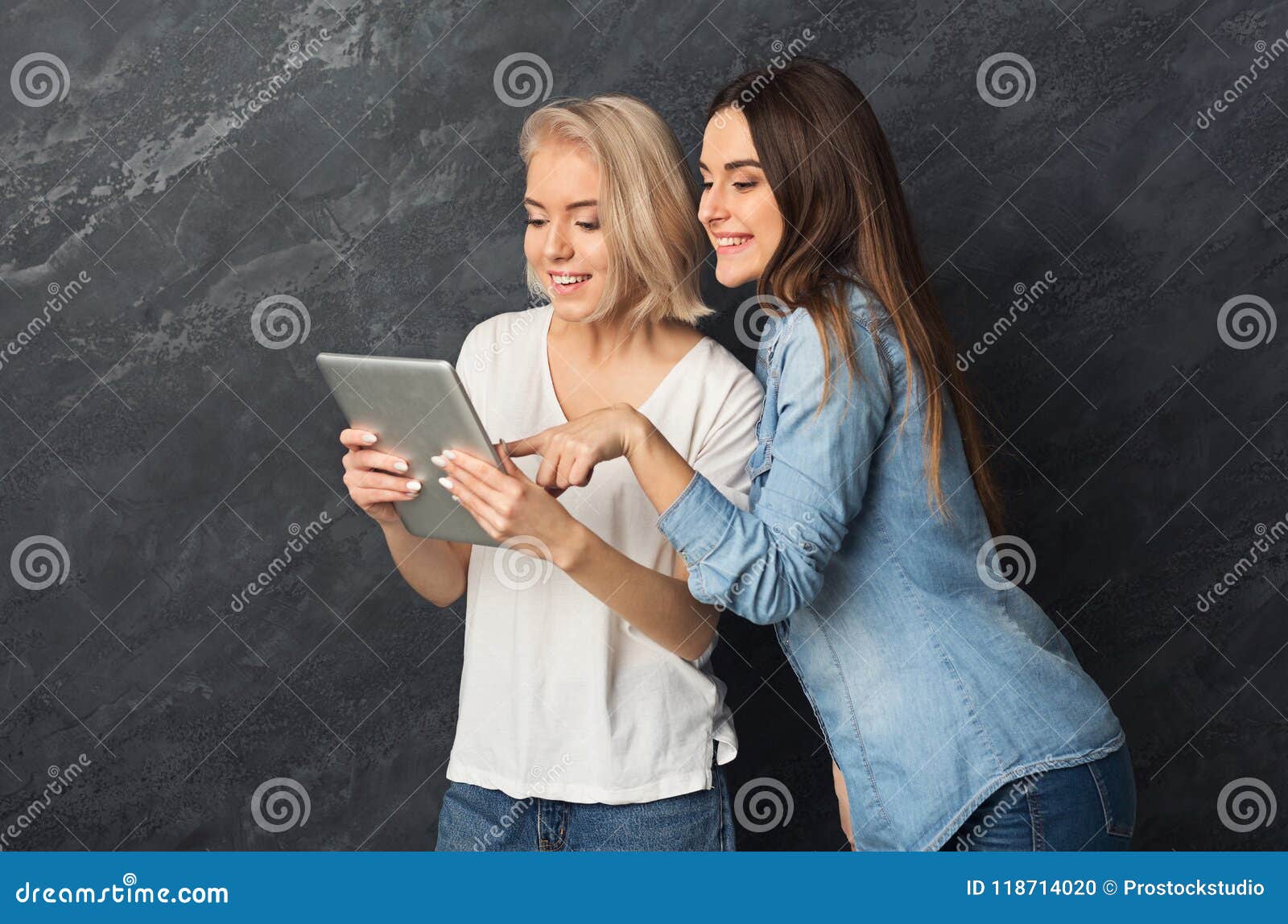 Curious Female Friends Using Tablet at Dark Studio Background Stock ...
