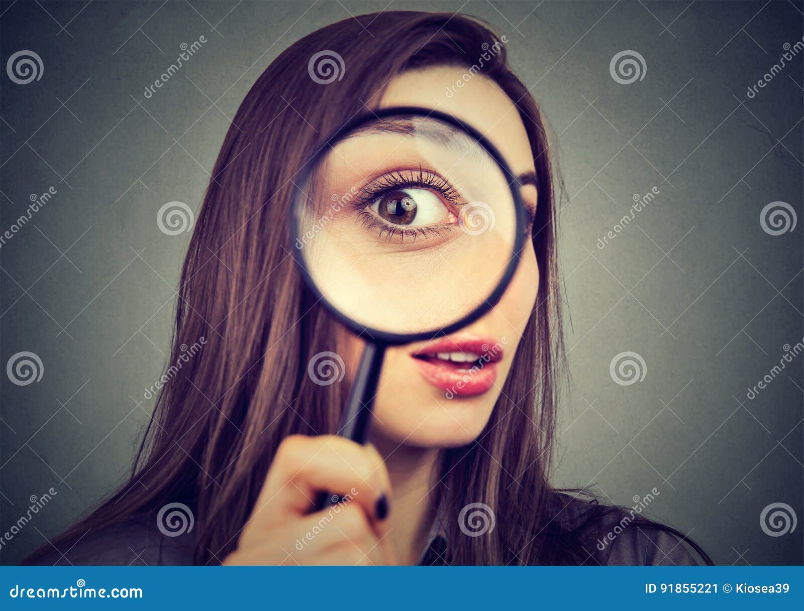 curious woman looking through a magnifying glass