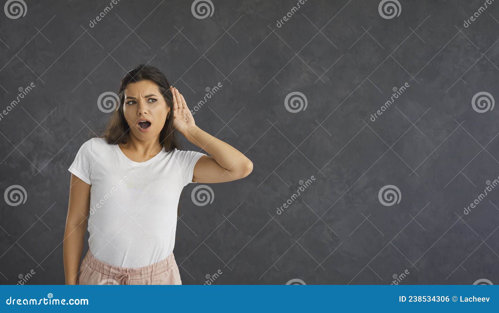 Curious Woman With A Shocked Expression Holds Her Hand Near Her Ear