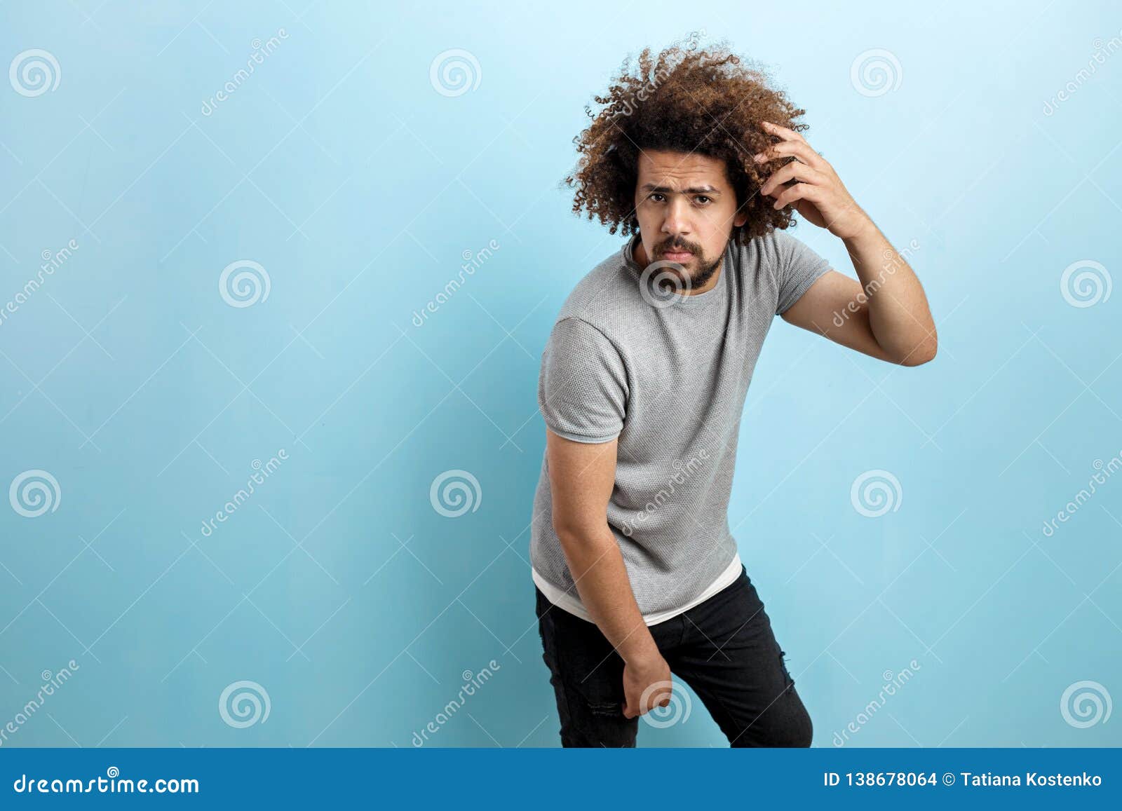 A Curly-headed Handsome Man Wearing a Gray T-shirt is Standing, Leaning ...