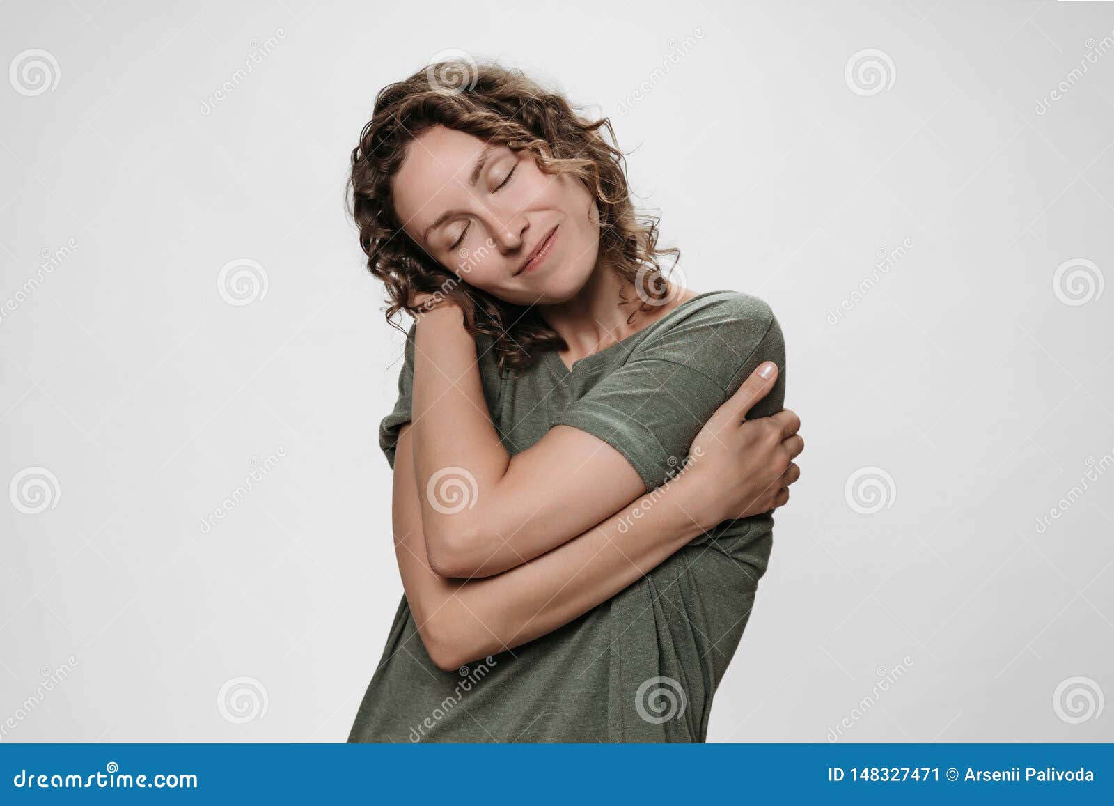 young curly woman hugging herself, looks happy, loves herself, has high self esteem