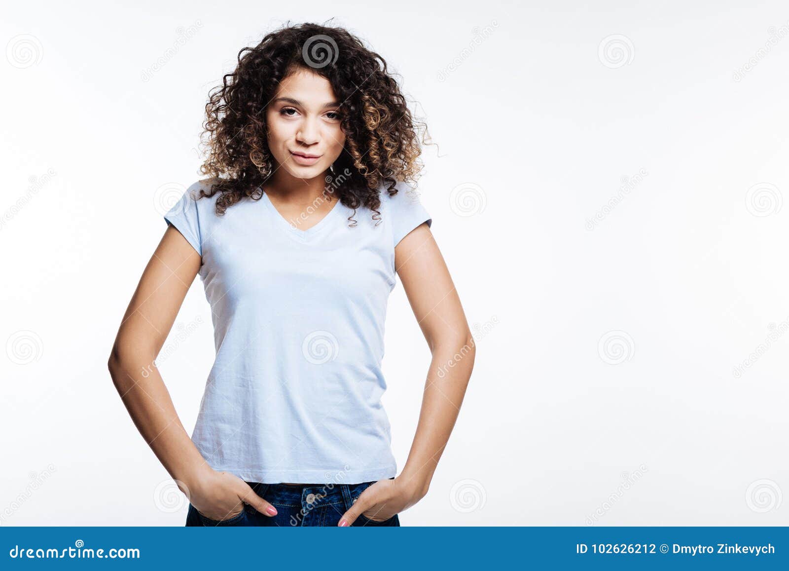Curly Young Woman Posing with Her Hands in Pockets Stock Photo - Image ...