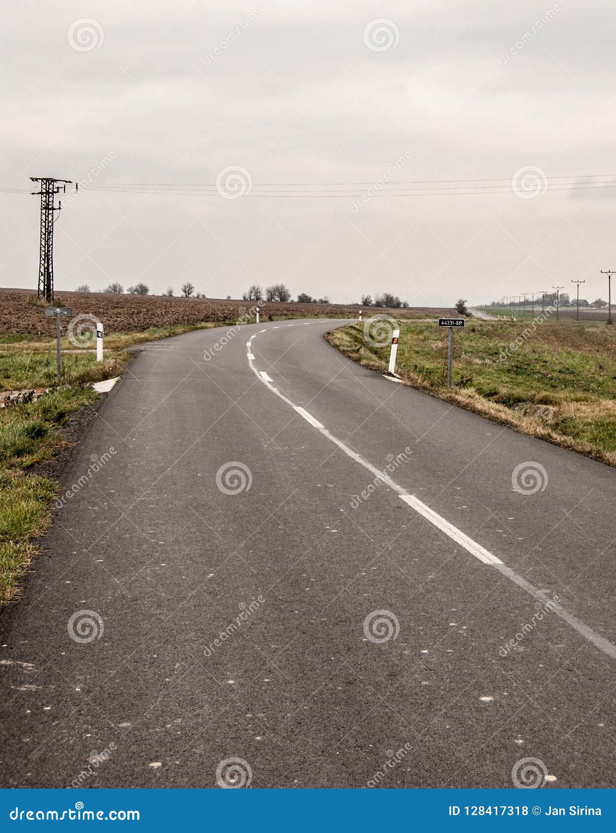 curving road with rural landscape around during cloudy autumn day