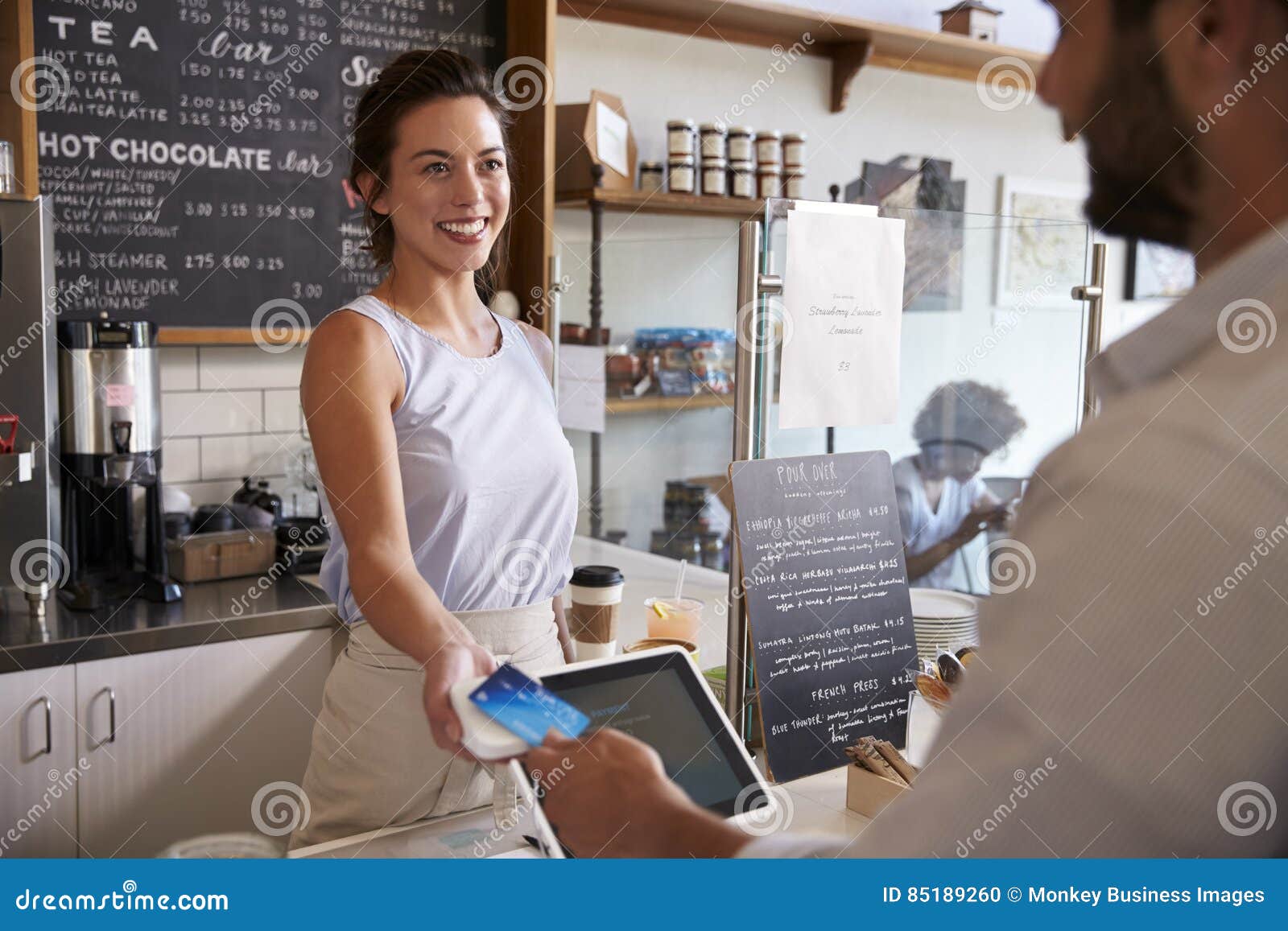 Customer at Coffee Shop Pays Smiling Waitress with Card Stock Photo