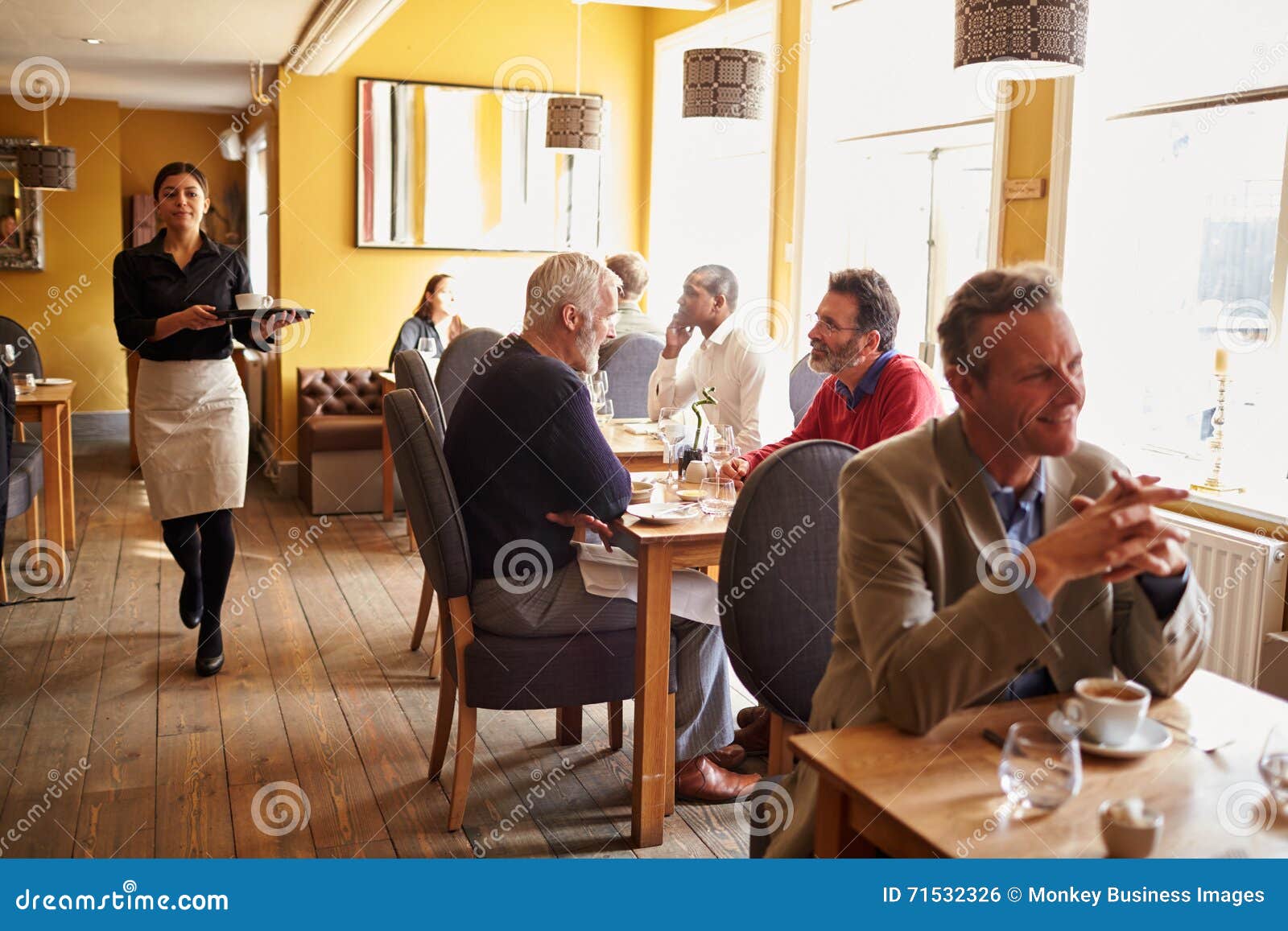 customers at tables and waitress in busy restaurant interior