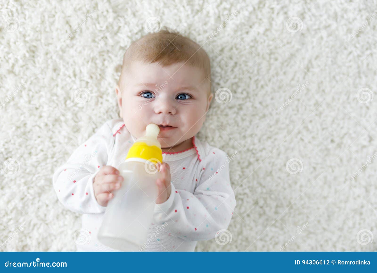 cute adorable ewborn baby girl holding nursing bottle and drinking formula milk