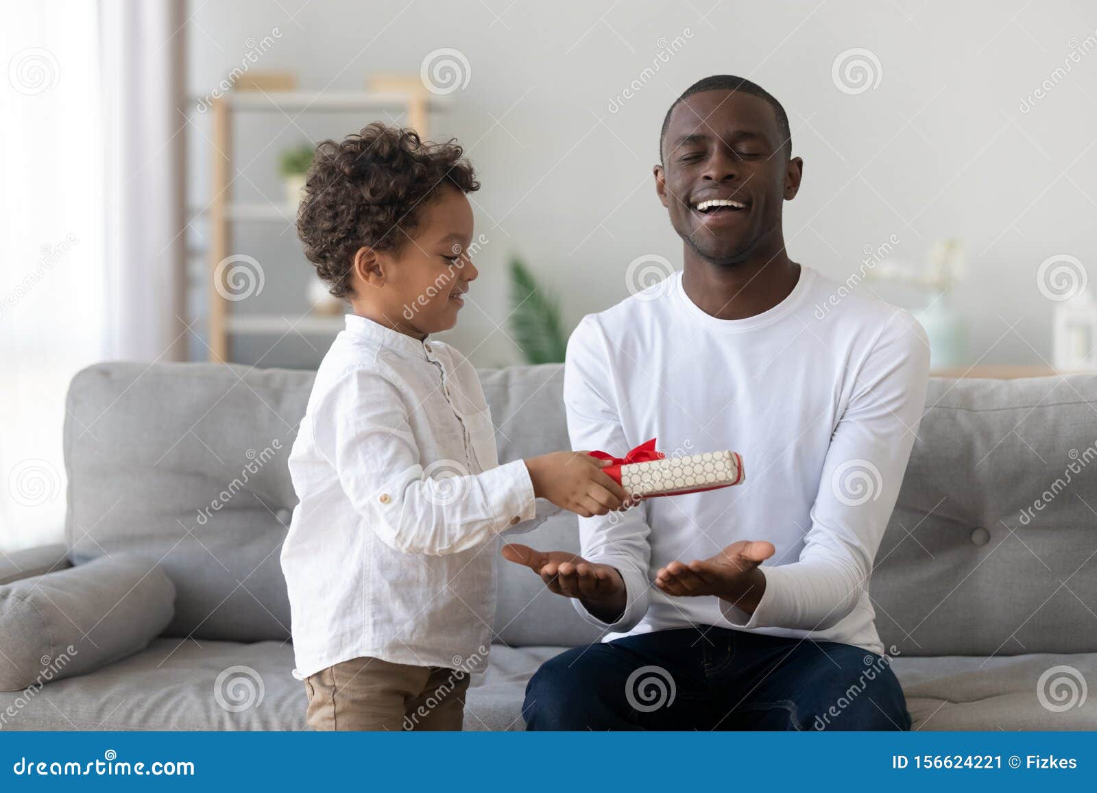 cute african kid son giving gift to dad fathers day
