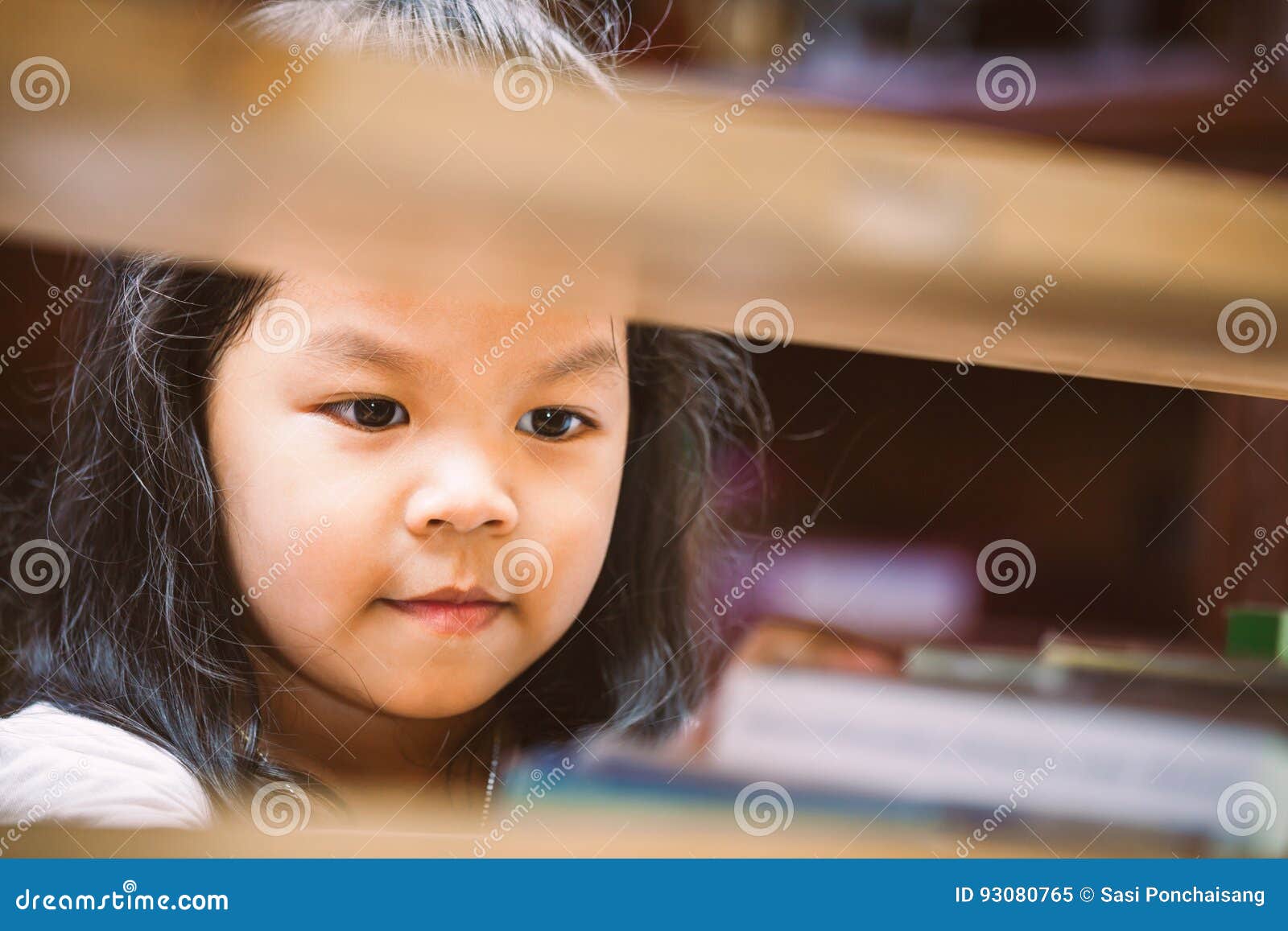 Cute Asian Little Girl Is Finding A Book On Bookshelf Stock Image