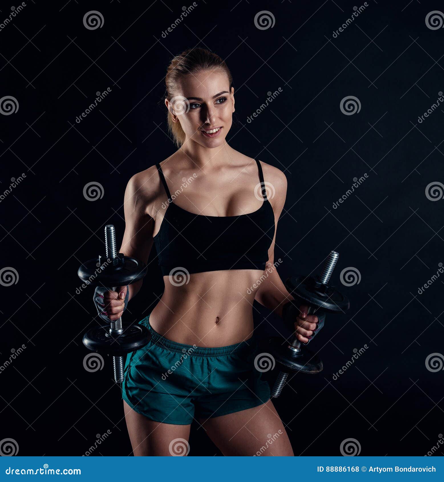 Cute Athletic Model Girl in Sportswear with Dumbbells in Studio