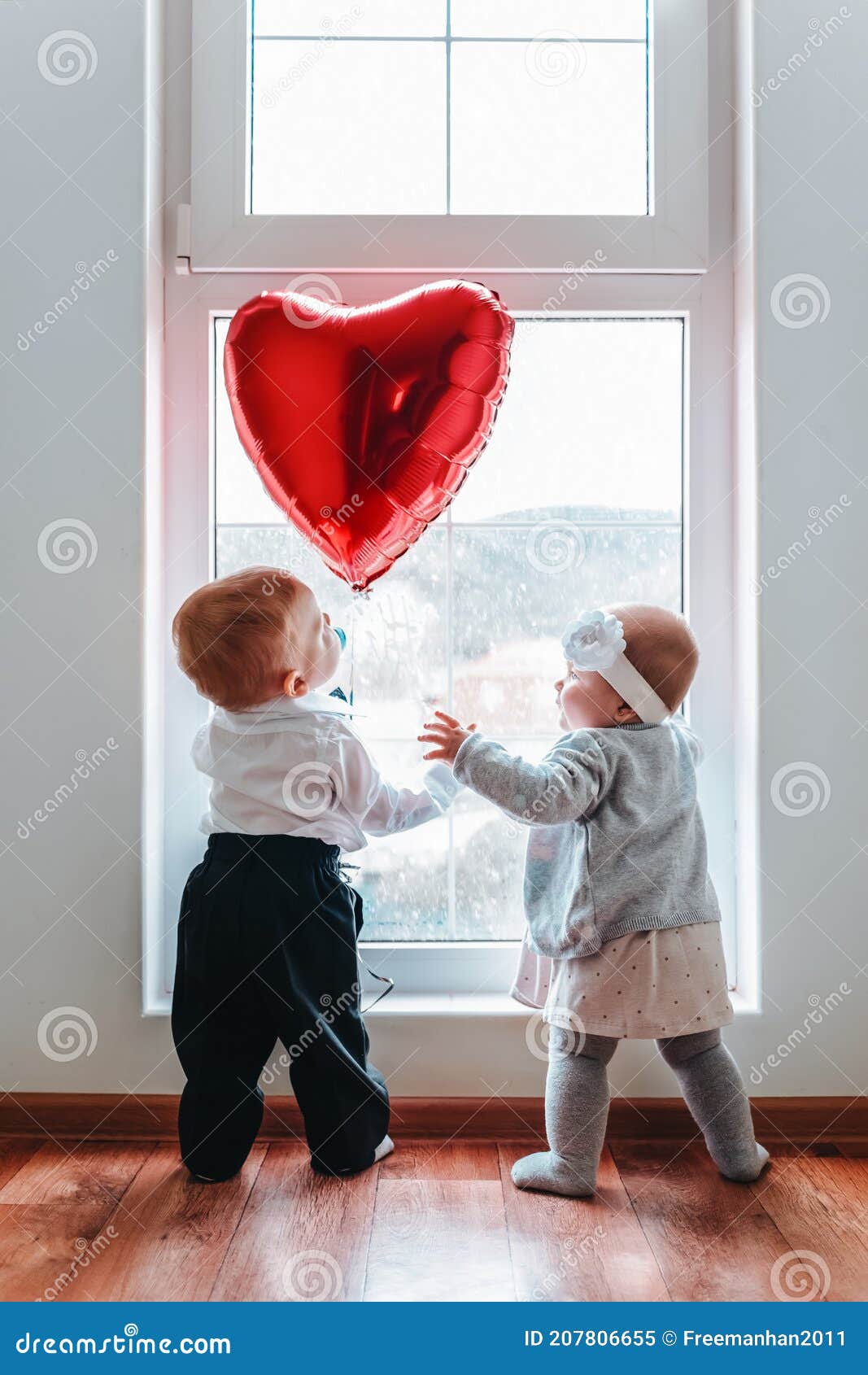 Cute Baby Boy and Baby Girl Looking at the Red Heart Balloon ...