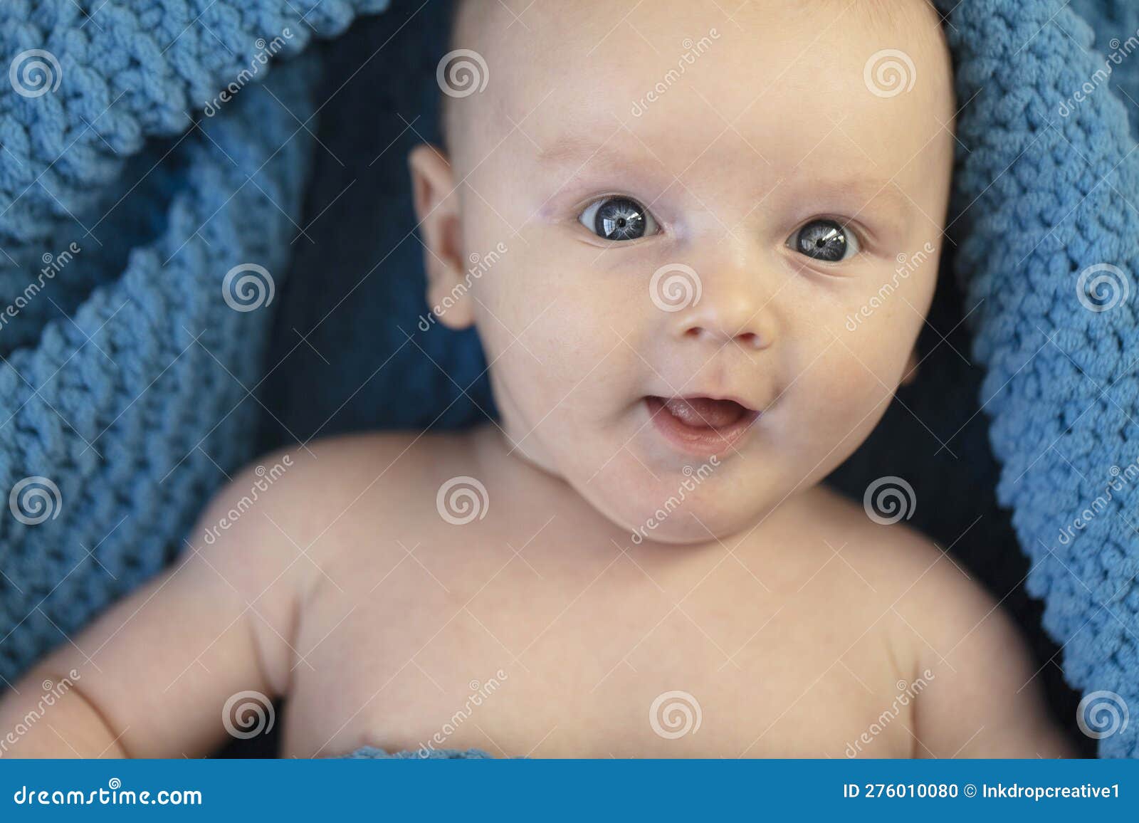 A Cute Baby Boy Wrapped in a Cosy Blue Blanket Looking at the Camera