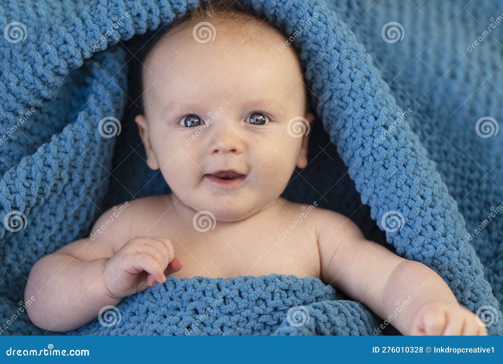 A Cute Baby Boy Wrapped in a Cosy Blue Blanket Looking at the Camera