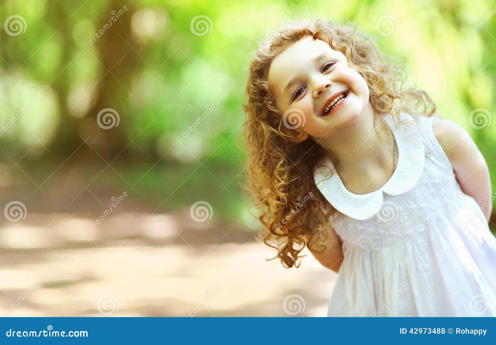 Cute thoughtful toddler girl with curly hair in casual clothe looking away  on pink background stock photo