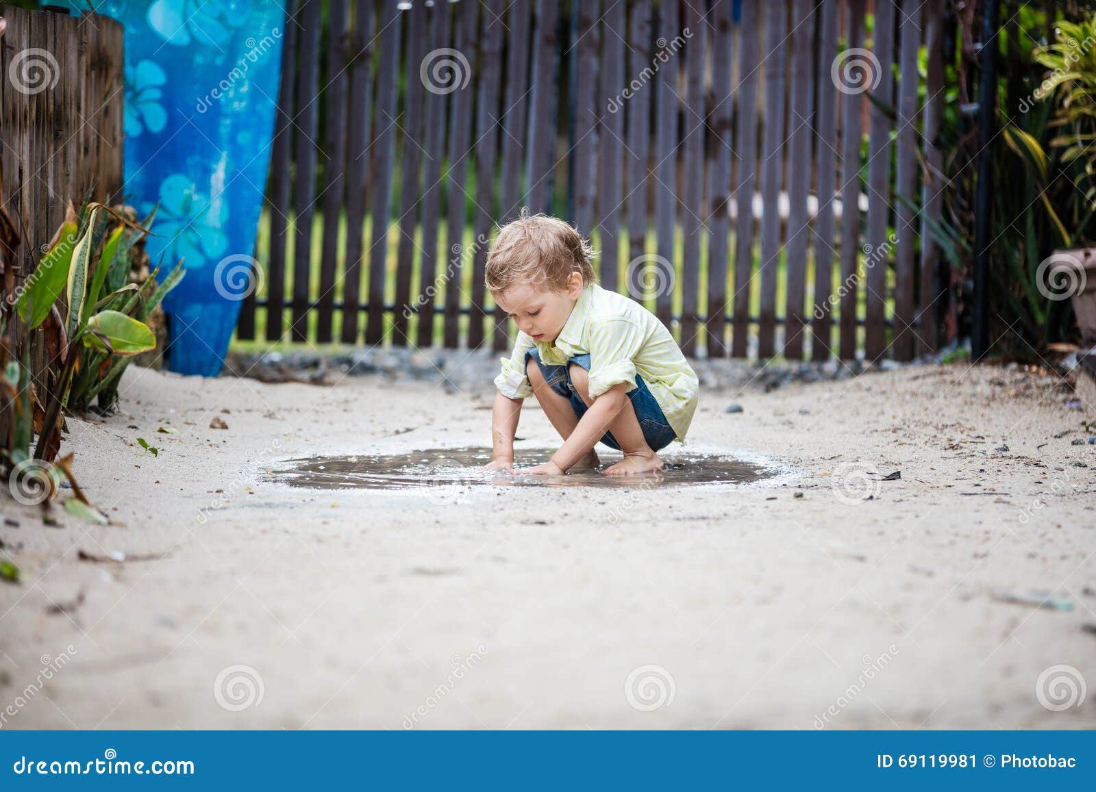 cute barefoot boy plunging hands in puddle