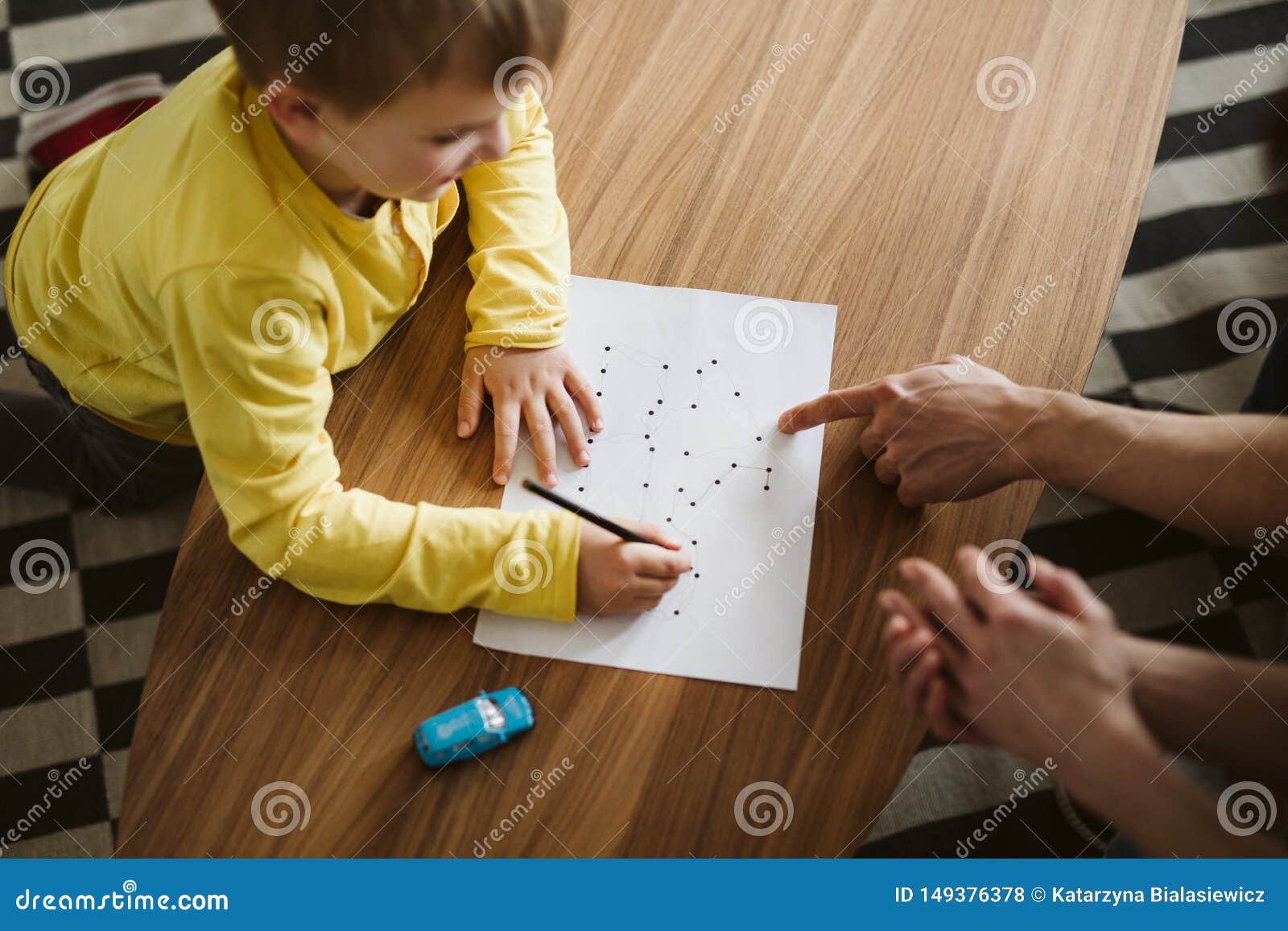 cute boy kneeling on the floor and connecting dots on a piece of paper