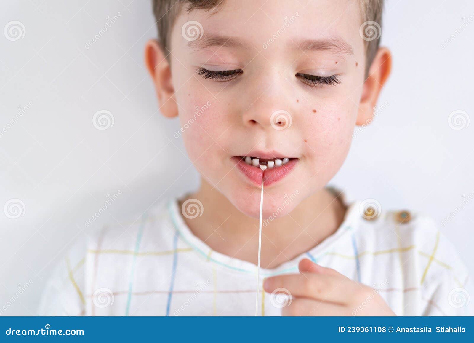 Cute Boy Pulling Loose Tooth Using a Dental Floss. Process of Removing