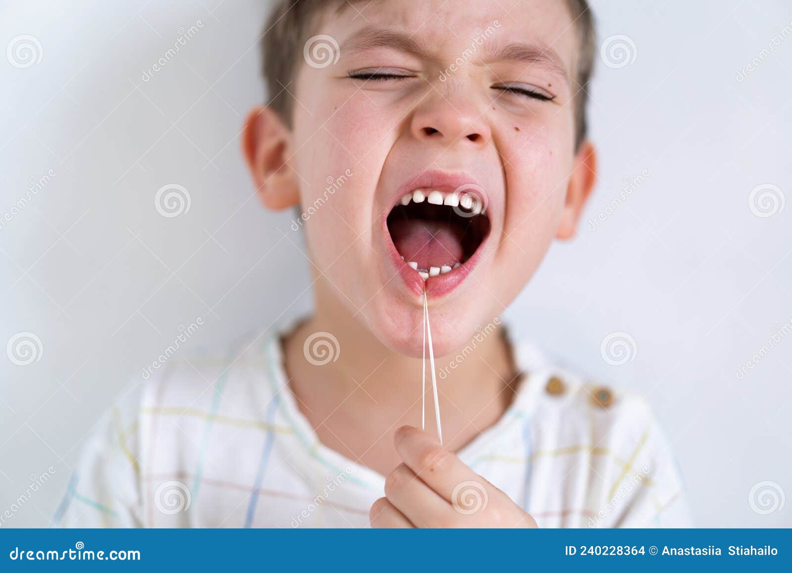 Cute Boy Pulling Loose Tooth Using a Dental Floss. Process of Removing