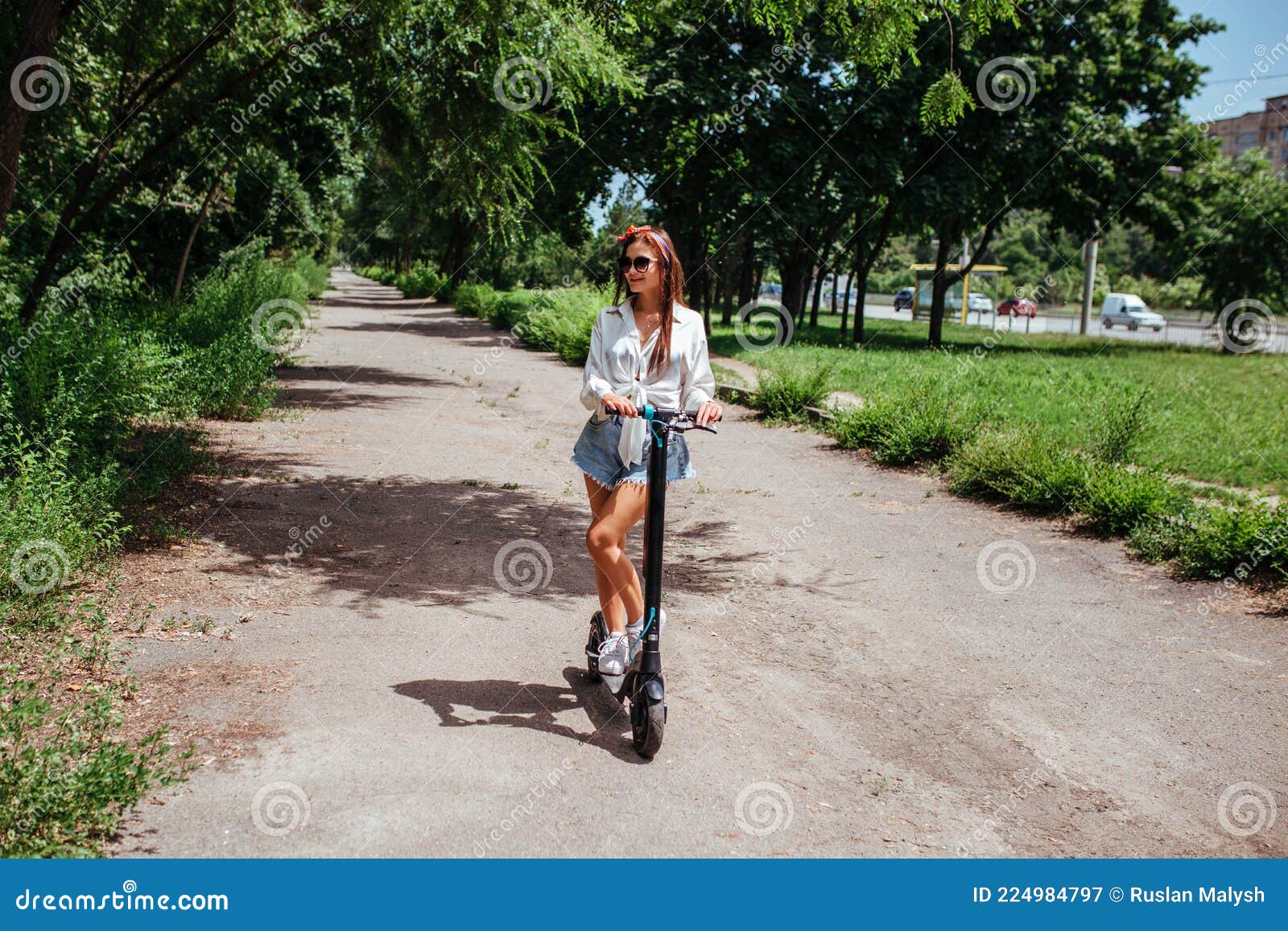 Cute Brunette Girl Rides on an Electric Scooter in the Park she is ...