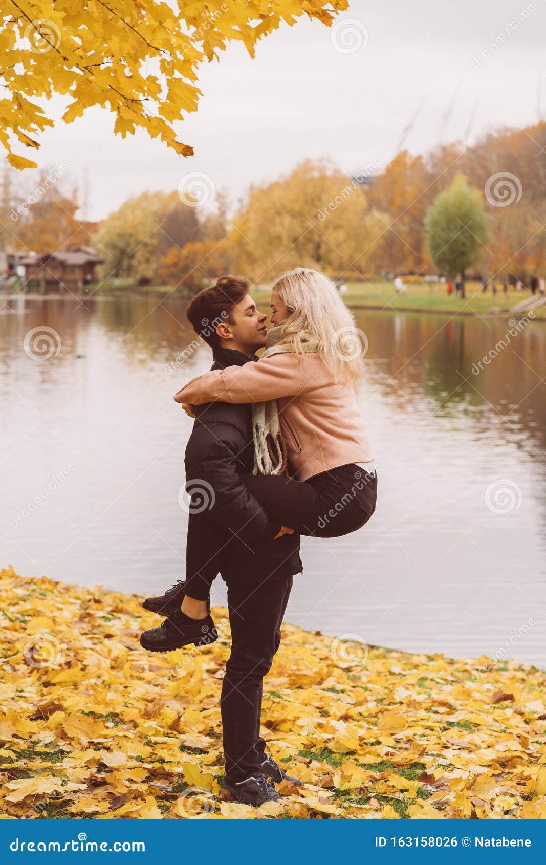 Cute Brunette Guy Holds In His Arms And Kisses A Beautiful Blonde Girl