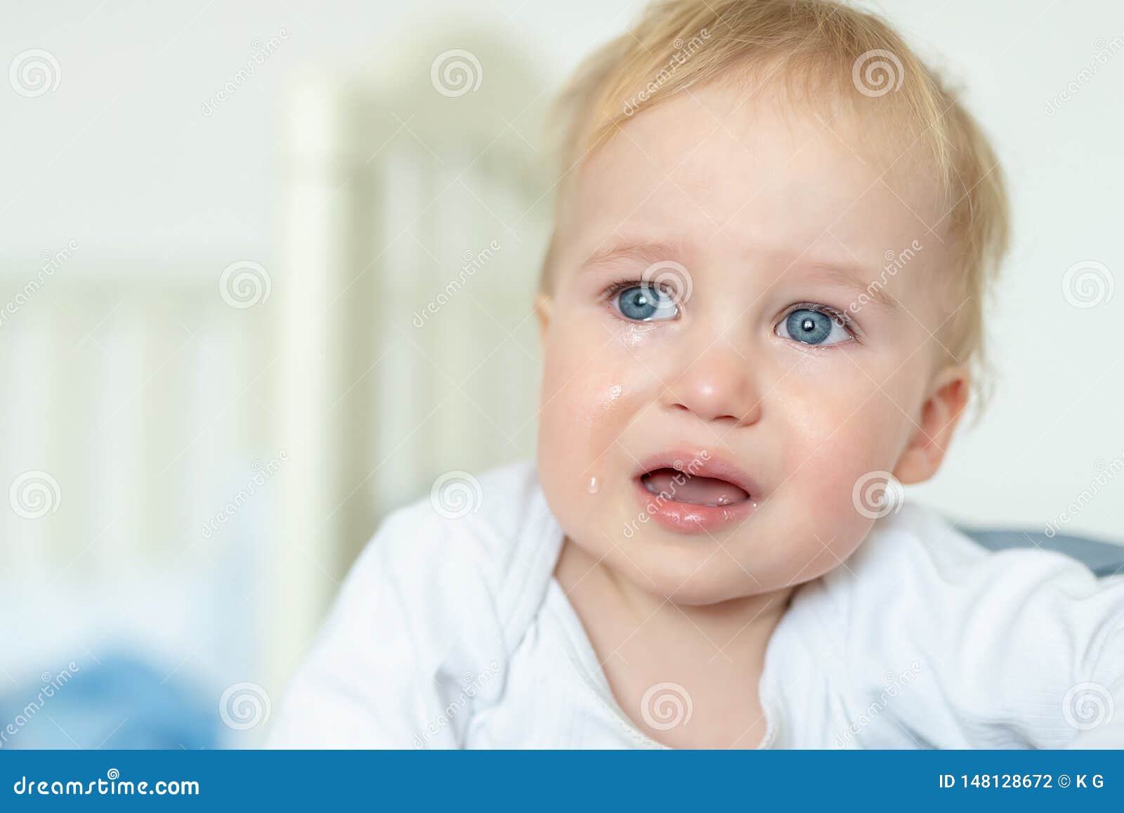 cute caucasian blond toddler boy portrait crying at home during hysterics. little child feeling sad. small pensive baby after