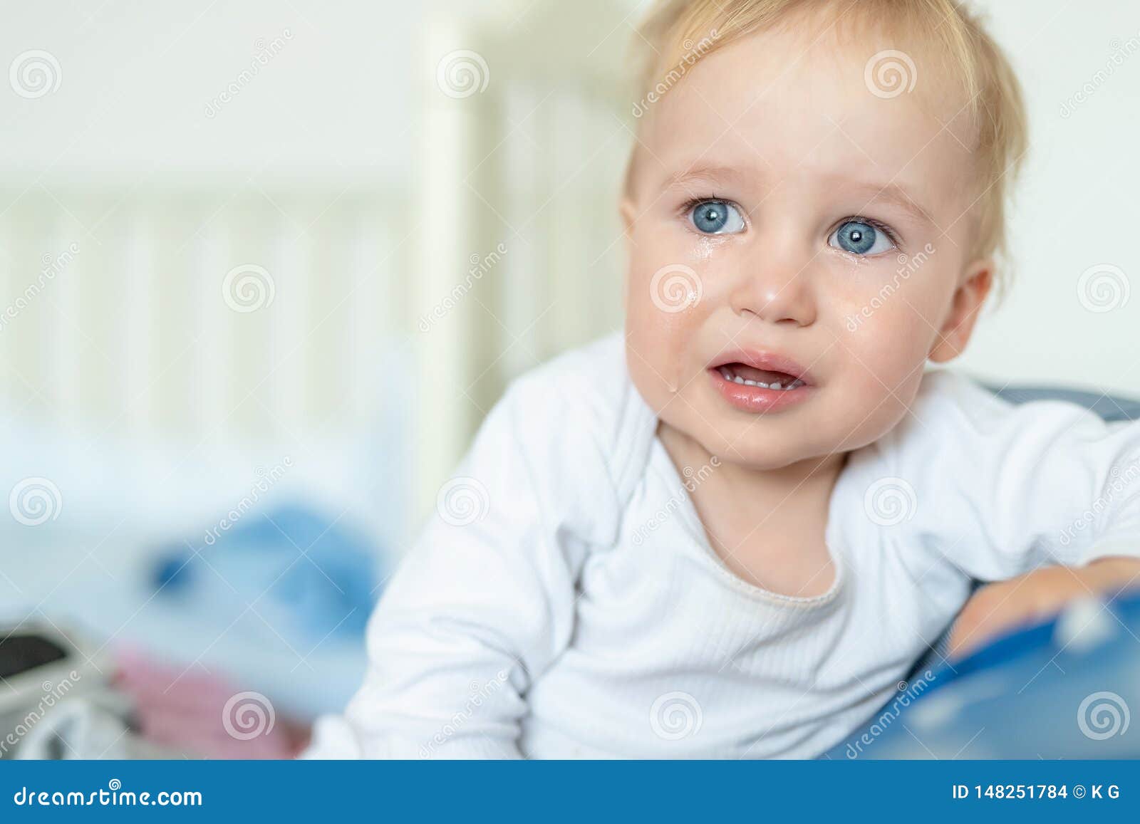 cute caucasian blond toddler boy portrait crying at home during hysterics. little child feeling sad. small pensive baby after