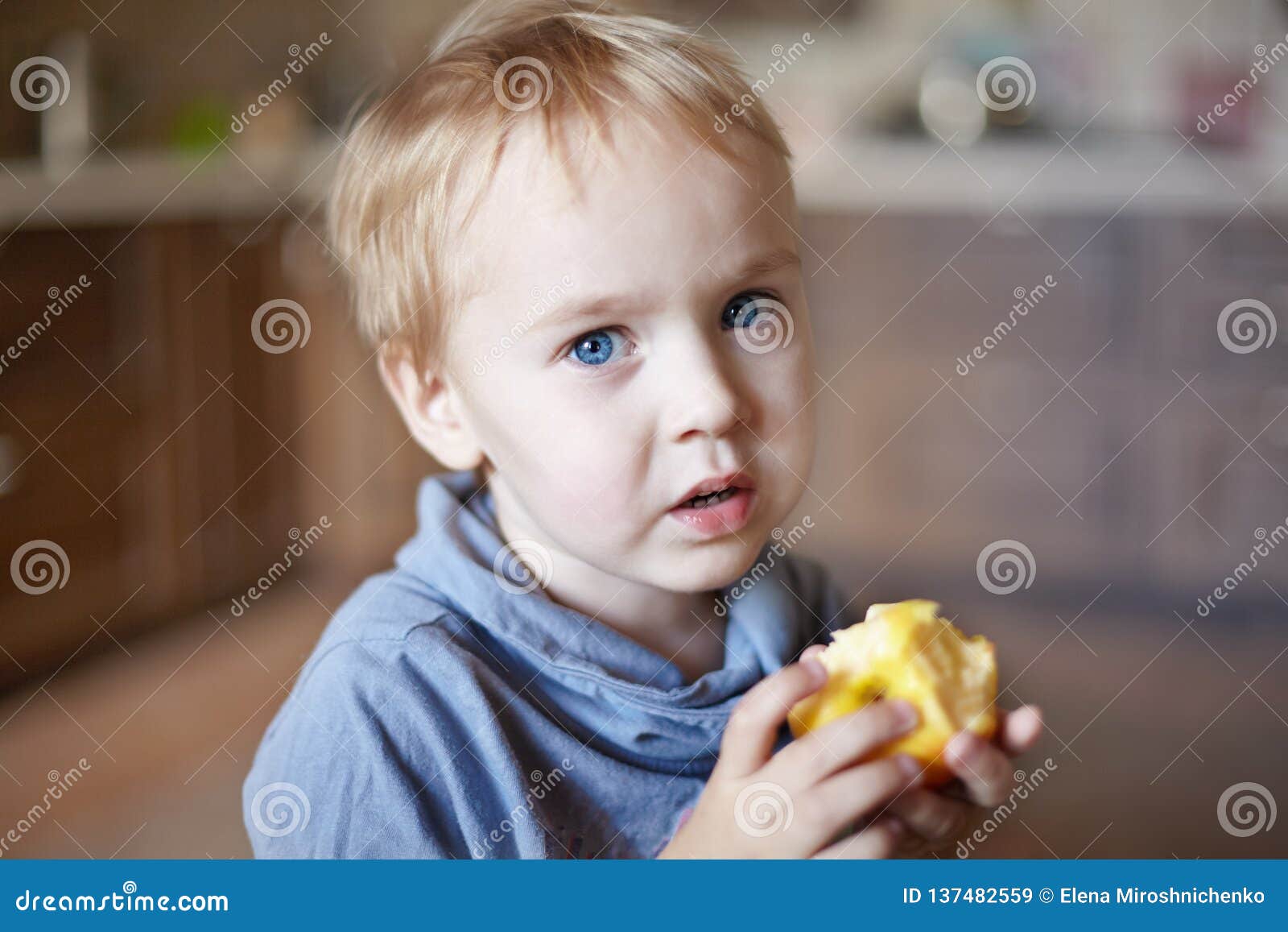 Cute Caucasian Little Boy With Blue Eyes And Blonde Hair Eats