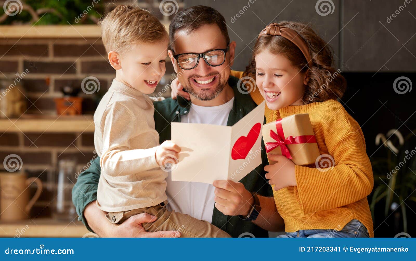 cute children congratulating happy daddy with fathers day and giving him handmade greeting postcard