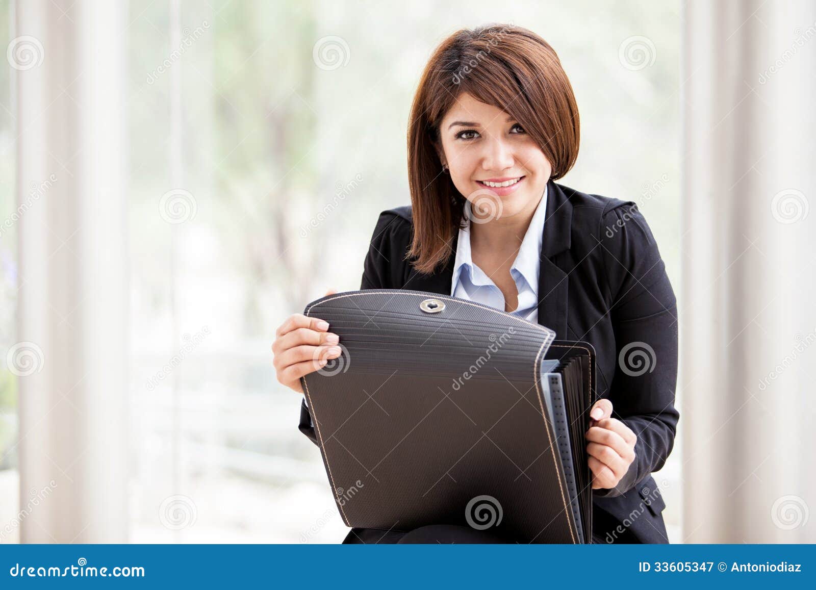 Cute female architect at work. Happy young female architect on a suit opening a briefcase and smiling