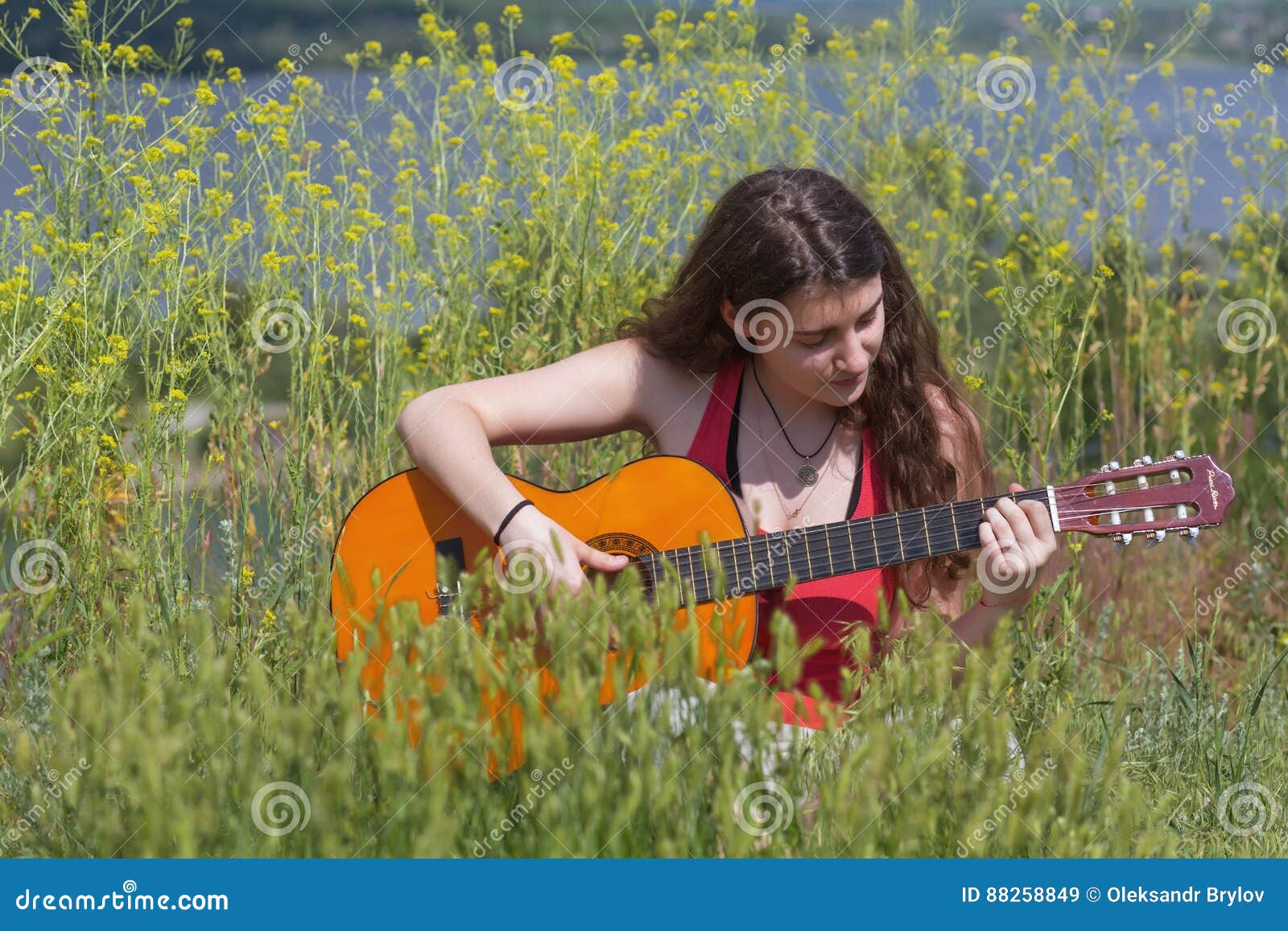 cute female musician sitting on green grass