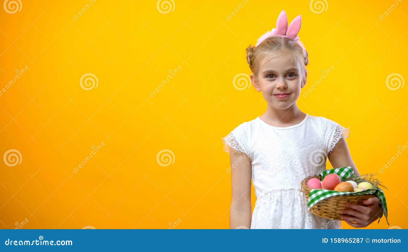 Cute girl in ears looking at camera, holding eggs basket, art school for young, stock photo