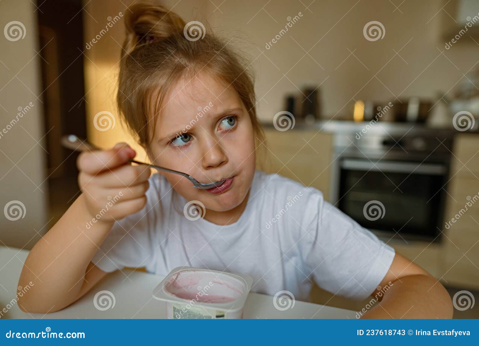 cute girl eats yogur with appetite, has dirty mouth, has fun, grimaces