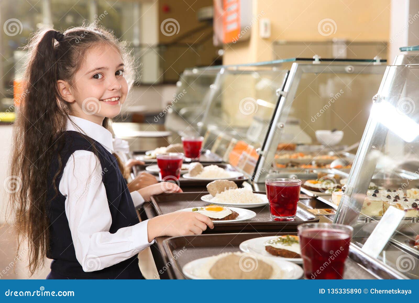 cute girl near serving line with healthy food in canteen