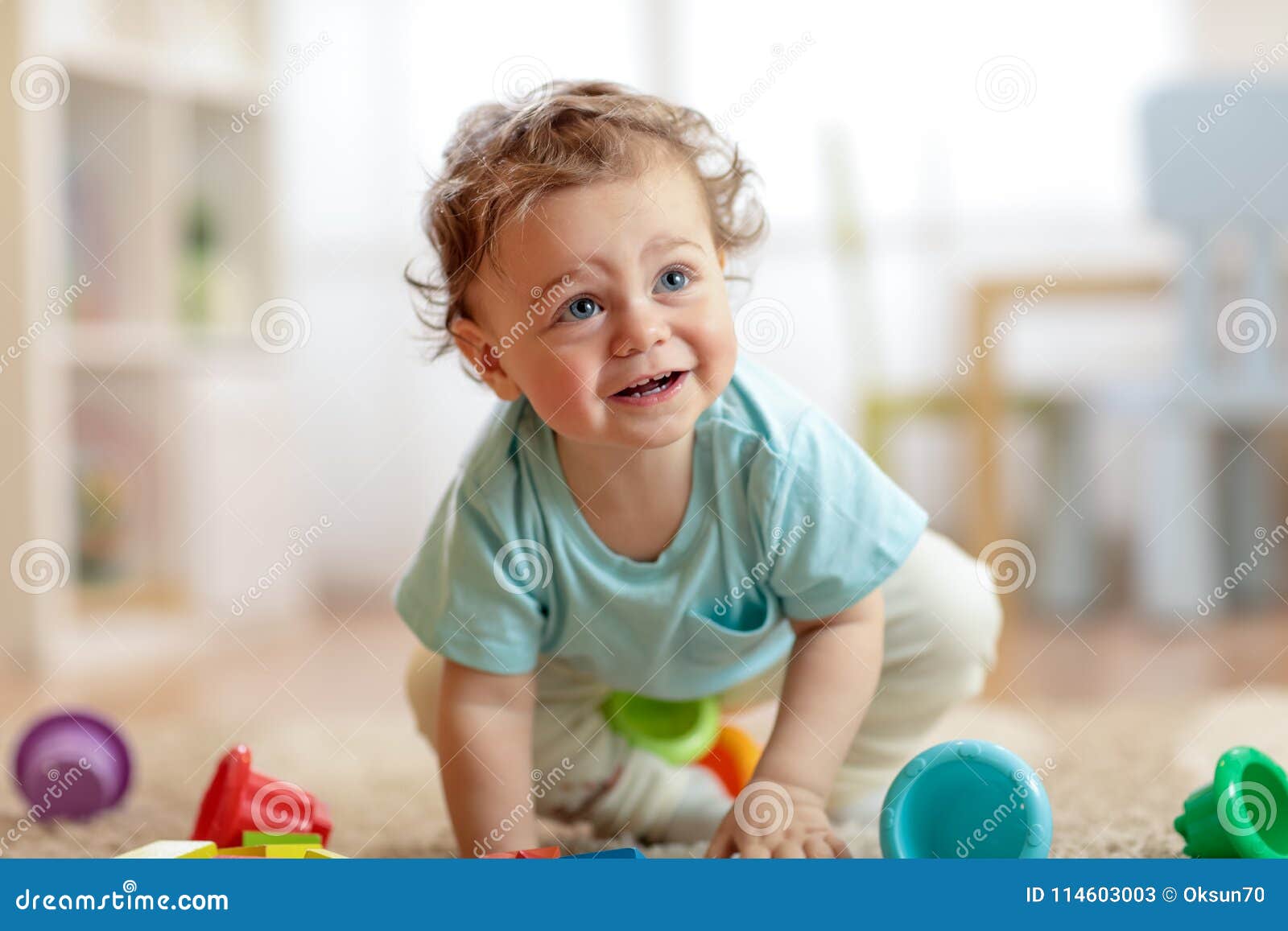 cute infant baby crawling on the floor at home, playing with colorful toys