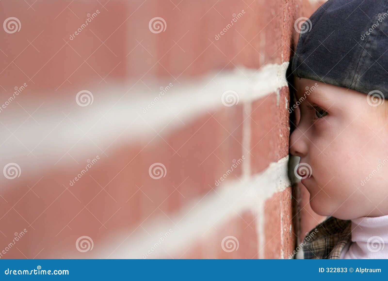 cute kid with nose squished against brick wall