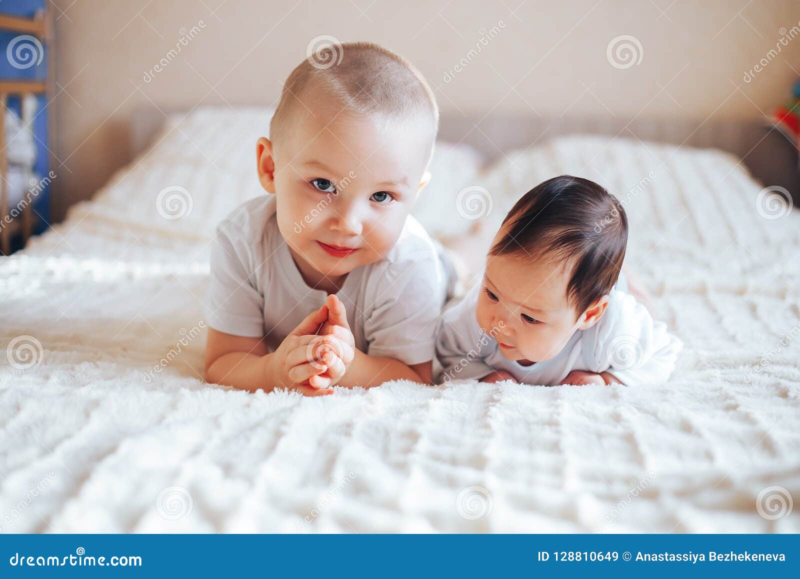 Cute Little Baby With Elder Brother Lying On Bed At Home Stock